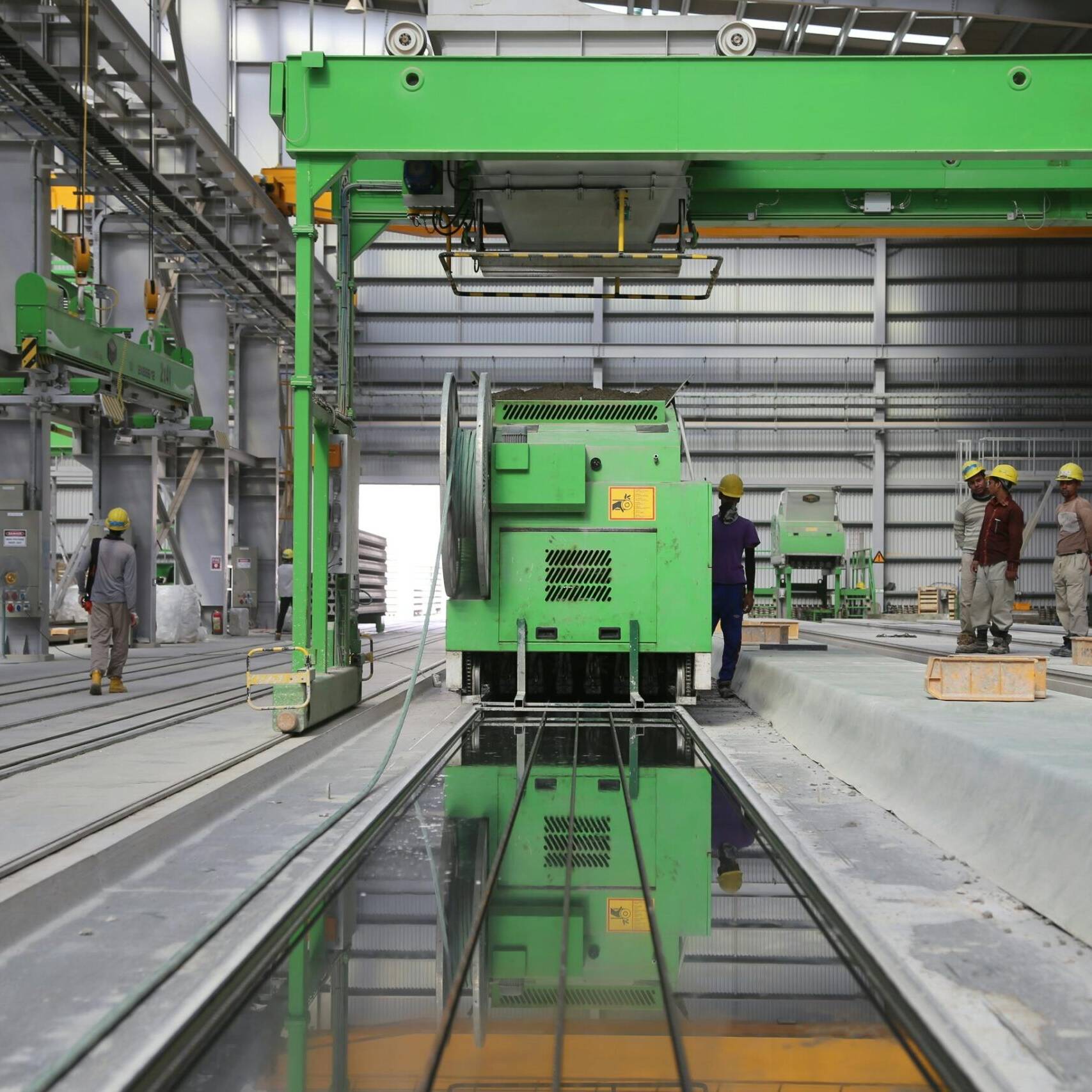 Factory workers standing next to a big green industrial machine