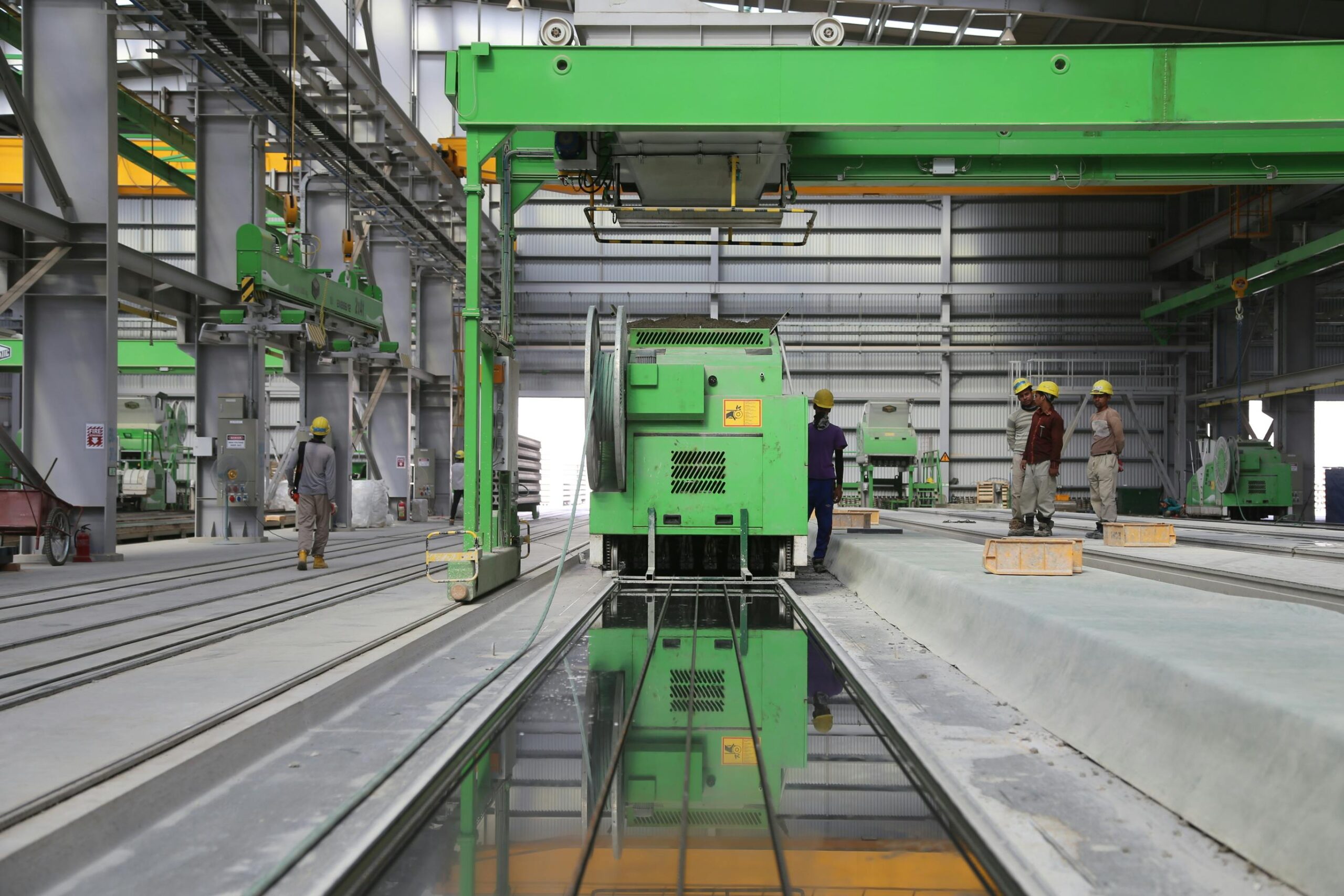 Factory workers standing next to a big green industrial machine