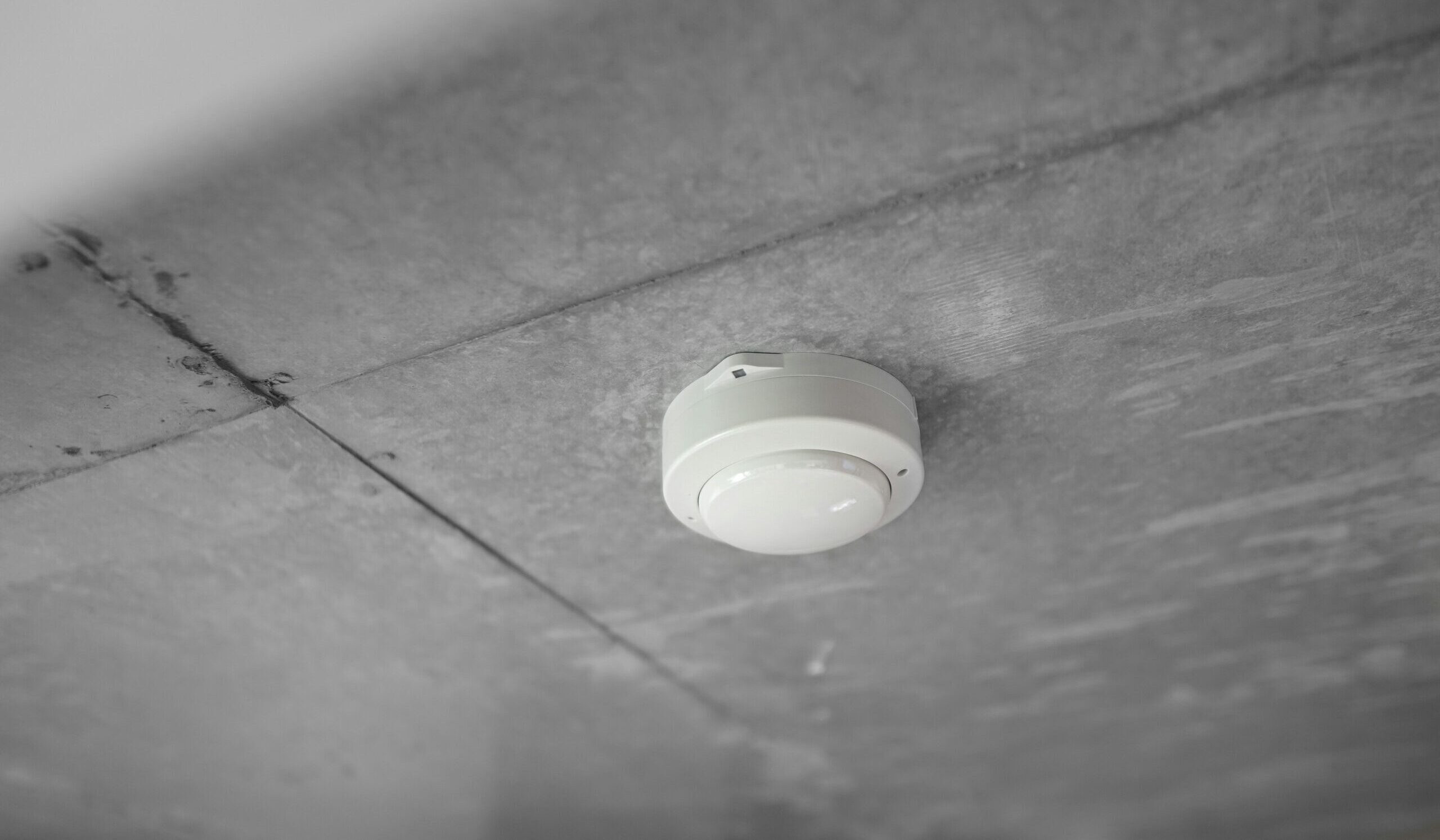 A fire alarm attached to a grey roof.